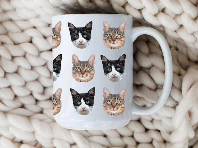 May include: White ceramic mug with a repeating pattern of black and brown cat faces. The mug has a large handle.