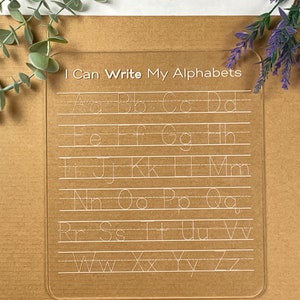 Könnte beinhalten: Ein transparentes Trockenlösch-Brett aus Kunststoff mit dem Text "I Can Write My Alphabets" oben. Das Brett hat Linien zum Üben des Schreibens der Buchstaben des Alphabets.