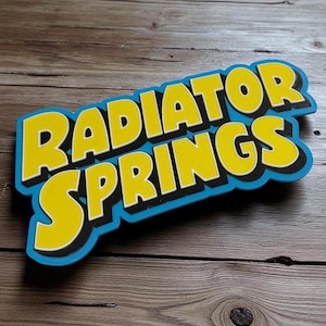 Peut inclure: Un panneau coloré avec l'inscription "RADIATOR SPRINGS" en jaune, soulignée de noir, sur fond bleu. Le panneau est incliné et semble être fait d'un matériau robuste, peut-être du bois ou du plastique.