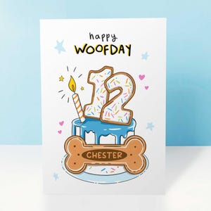 May include: A birthday card with the words "happy WOOFDAY" in black and yellow. The card features a blue cake with the number 12 on top, decorated with sprinkles. A bone-shaped cookie with the name "CHESTER" is at the bottom.