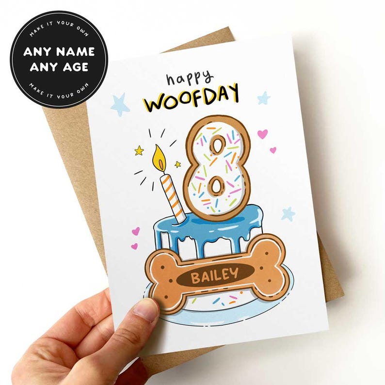 May include: A birthday card with a dog bone and cake design. The card says "happy WOOFDAY" and features a number 8 donut with sprinkles and a lit candle. The dog bone has the name "BAILEY" on it. The card is held in a hand.