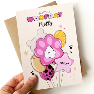 K&ouml;nnte beinhalten: Eine rosa und wei&szlig;e Geburtstagskarte mit dem Text "Happy Woofday Molly" und einem Pfotenballon mit der Nummer 4. Die Karte hat ein rosa, gelbes und wei&szlig;es Ballon-Thema mit Pfotenabdr&uuml;cken und Sternen.