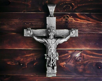 May include: A silver-toned pendant in the shape of a crucifix with a detailed skeletal figure of a person on the cross. The pendant is hanging on a wooden surface.