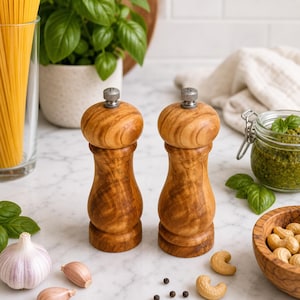 May include: Two wooden salt and pepper grinders with a natural grain finish and silver-colored metal knobs on top. The left grinder is marked with a P and the right grinder is marked with an S on the top metal adjustment knob.
