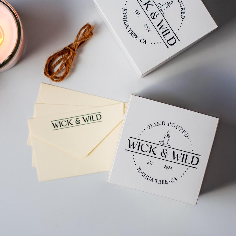 Custom logo rubber stamp on white product box lid and branded envelopes showing consistent candle business branding across multiple packaging surfaces