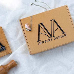 Custom logo rubber stamp made of wood on kraft mailer box with sharp monogram impression for jewelry brand and boutique business packaging
