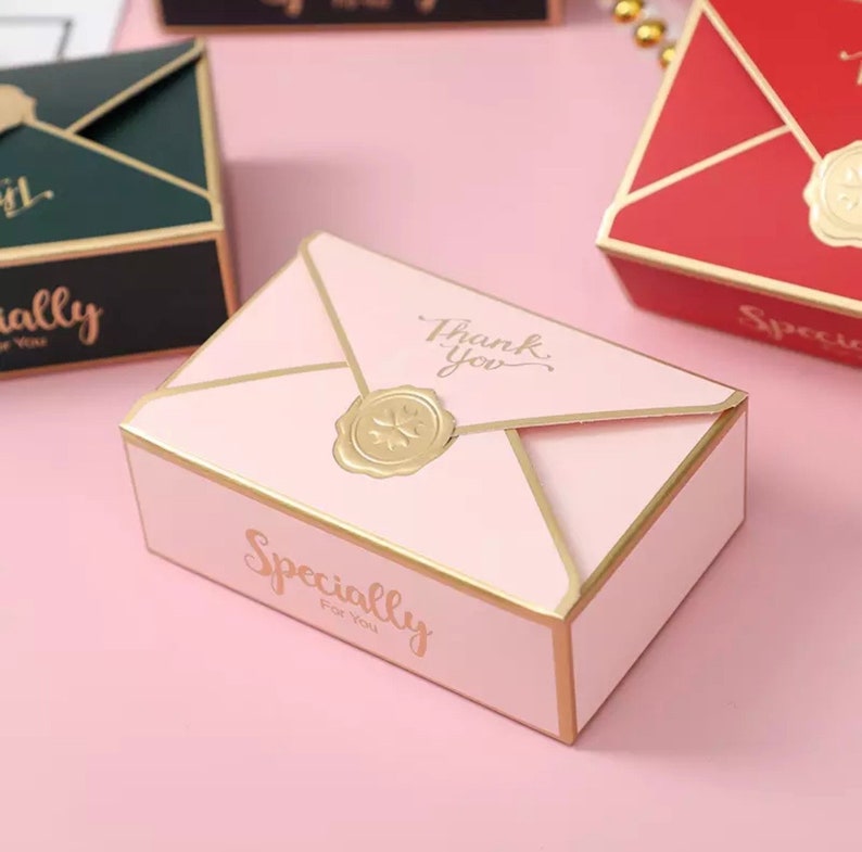 May include: Pink envelope-shaped gift box with gold trim and a gold wax seal. The box has the text "Thank you" and "Specially for you" printed on it.
