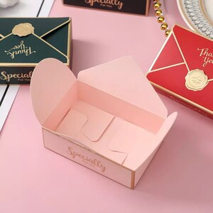 May include: Pink and gold envelope-shaped gift box with the words "Specially For You" printed on the front. The box is open and the inside is empty.