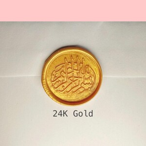 May include: A gold wax seal with Arabic calligraphy. The seal is round and has a raised design. The text below the seal reads "24K Gold".