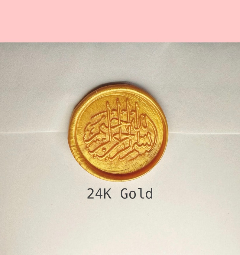 May include: A gold wax seal with Arabic calligraphy. The seal is round and has a raised design. The text below the seal reads "24K Gold".