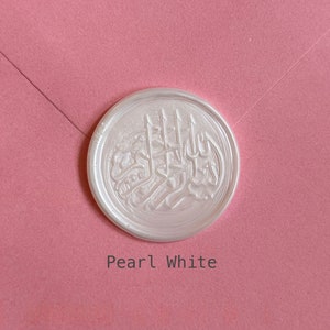 May include: A white wax seal with an Arabic calligraphy design. The seal is on a pink background and the text "Pearl White" is below the seal.