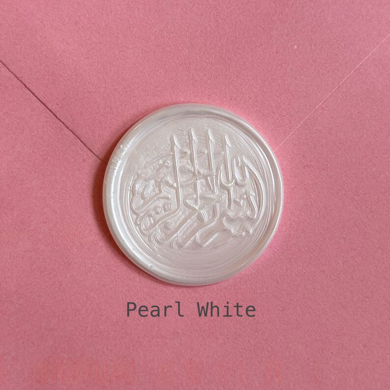 May include: A white wax seal with an Arabic calligraphy design. The seal is on a pink background and the text "Pearl White" is below the seal.