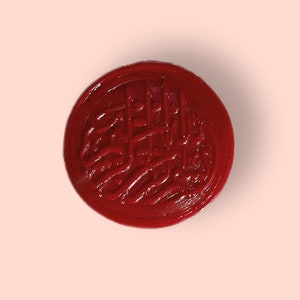 May include: A red wax seal with a decorative design. The seal is round and has a raised design.