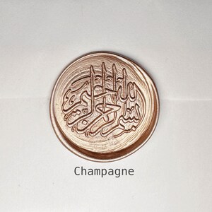 May include: A round, gold-colored wax seal with an intricate Arabic calligraphy design. The seal is labeled "Champagne".