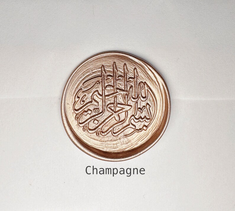 May include: A round, gold-colored wax seal with an intricate Arabic calligraphy design. The seal is labeled "Champagne".