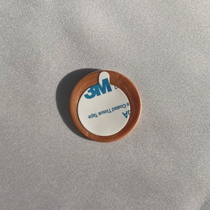 May include: A round, copper-colored adhesive sticker with a white label that reads "3M  94  e Coated Tissue Tape".