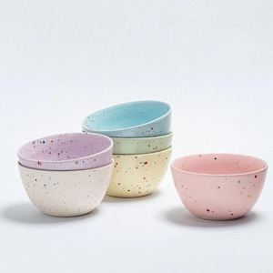 Op de afbeelding: Set van zes gespikkelde keramische kommen in pastelkleuren, waaronder lichtblauw, lichtgroen, lichtpaars en roze.