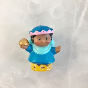 May include: A blue and pink plastic figurine of a wise man holding a gold star. The figurine is part of a nativity set.