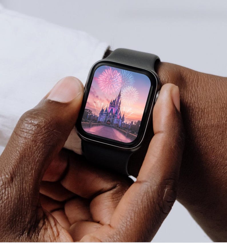 May include: A black smartwatch with a square face displaying a photo of Cinderella's castle at Walt Disney World with fireworks in the sky.