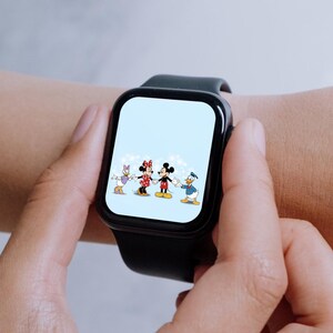 Puede incluir: Un reloj inteligente negro con un fondo blanco que muestra una imagen de dibujos animados de Mickey Mouse, Minnie Mouse, Donald Duck y Daisy Duck. Los personajes sonr&iacute;en y se toman de la mano.