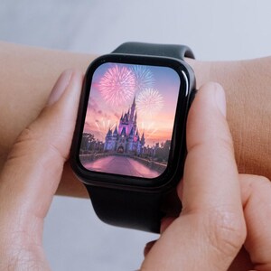 May include: A black smartwatch with a digital display showing a picture of Cinderella's Castle at Walt Disney World with fireworks in the sky.