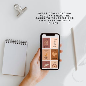 May include: A smartphone displaying affirmation cards with illustrations and text. The cards include phrases like "I am Grateful", "I am a Leader", "I Choose to be Positive Today", and "I am Successful".