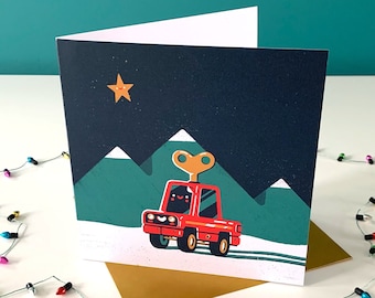 May include: A red toy truck with a wind-up key on the roof drives through a snowy landscape with green hills and a yellow star in the night sky.