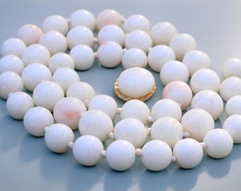 May include: A white pearl necklace with a gold clasp. The pearls are round and have a slight iridescent sheen.