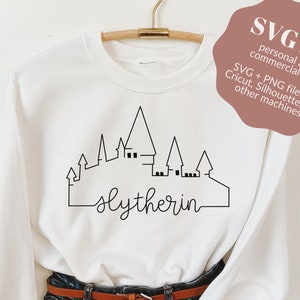 May include: White sweatshirt with a black outline of Hogwarts castle and the text "Slytherin" in cursive.