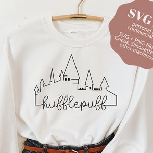 May include: White sweatshirt with a black outline of a castle and the text "hufflepuff" in black cursive lettering.