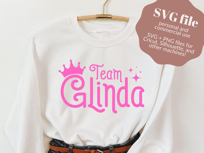 Pu&ograve; includere: Felpa bianca con una corona rosa, le parole "Team Glinda" e stelle scintillanti.