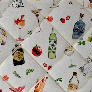 May include: A white fabric notice board with a repeating pattern of gin bottles, cocktails, limes, and strawberries. The text "Clink Clink", "Summer in a Glass", "Twist of Lime", and "Gin" are printed on the fabric.