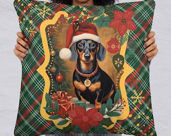 Può includere: Un cuscino decorativo natalizio con un bassotto che indossa un cappello da Babbo Natale e un collare festivo. Il cane è ambientato in una scena natalizia con un albero, ornamenti e regali, il tutto incorniciato da un motivo a quadri rossi, verdi e oro.