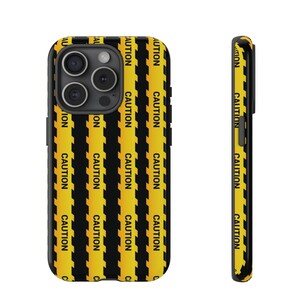 May include: A black phone case with a yellow and black caution tape pattern. The case has a cutout for the camera lens and a black border.