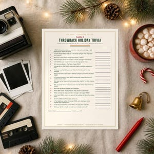 May include: A printed trivia game sheet titled Throwback Holiday Trivia with twenty numbered questions, surrounded by a vintage camera, two cassette tapes, a mug of hot cocoa with marshmallows, a candy cane, a bell, and a red pen.
