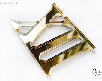 May include: A gold-colored acrylic letter "E" with a reflective surface. The letter is part of the "ROMA MOD. B" series. The image also includes the "Glow Me" logo and "MADE IN ITALY" text.