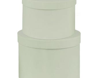 May include: Two round, pale green gift boxes stacked on top of each other. The boxes are made of cardboard and have a smooth, matte finish.