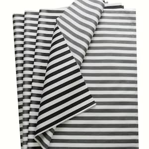 May include: A stack of rectangular sheets of thin, semi-transparent paper featuring a repeating pattern of horizontal black and white stripes. The top sheet is folded over at the corner, revealing the consistent striped design on both sides of the paper.
