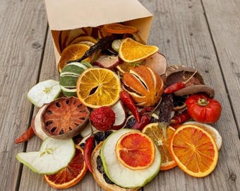 Könnte beinhalten: Eine braune Papiertüte, aus der eine Vielzahl getrockneter Fruchtscheiben wie Orange, Limette, Apfel und Grapefruit herausfällt, vermischt mit ganzen getrockneten Chilischoten und anderen botanischen Elementen, ein buntes Sortiment.