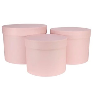 Pode incluir: Três caixas de presente redondas rosa claro com tampas a condizer. As caixas são de tamanhos diferentes e estão agrupadas. As caixas são feitas de um material liso e adequadas para várias ocasiões de oferta.