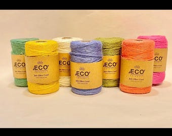May include: A collection of seven spools of jute fiber cord in various colors including yellow, green, white, blue, orange, and pink. Each spool features a brown paper label with the text ECO FRIENDLY Jute Fibre Cord 100% Natural Jute.