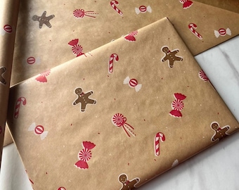 May include: A roll and a folded sheet of brown kraft wrapping paper featuring a repeating pattern of brown gingerbread men, red and white striped candy canes, and red and white wrapped candies scattered across the surface.