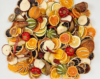 Könnte beinhalten: Eine Ansammlung von getrockneten Obstscheiben und ganzen getrockneten Paprikaschoten. Das Sortiment umfasst dehydrierte Orangen-, Zitronen- und Limettenscheiben sowie dunkelbraune getrocknete Fruchtstücke und leuchtend rote, runzlige Chilischoten.