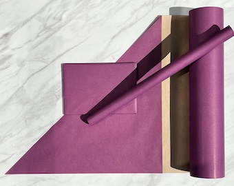 May include: A collection of deep purple wrapping paper featuring a large flat sheet, a smaller rectangular folded piece, and two cylindrical rolls of varying sizes, all displaying a solid matte finish and consistent color throughout.