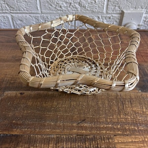 May include: A gold wire mesh basket with a woven base. The basket is empty and has a square shape with rounded corners.