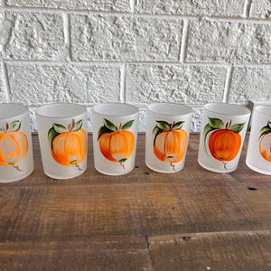 May include: Set of six frosted glass tumblers with hand-painted orange fruit designs. Each glass features a single orange with green leaves.