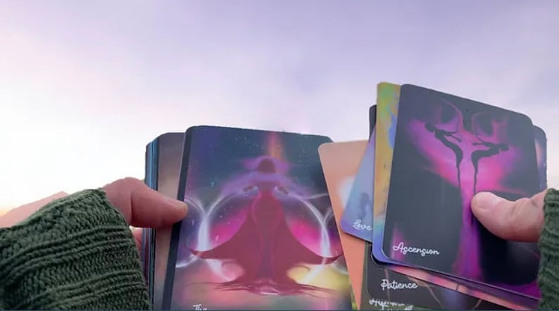 K&ouml;nnte beinhalten: Ein Deck Orakelkarten mit farbenfrohen, abstrakten Designs. Die Karten zeigen Bilder von Figuren und Symbolen, und der Text "Aufstieg", "Geduld" und "Liebe" ist auf den Karten sichtbar.