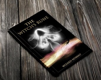 Könnte beinhalten: Ein schwarzes Buch mit dem Titel "The Witch's Rune" mit einem weißen und grauen ätherischen Design auf dem Cover. Das Buch liegt auf einer dunklen Holzoberfläche. Der Name des Autors, "Wizard Nomad", ist unten aufgedruckt.
