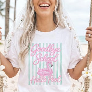 May include: White t-shirt with the text "Goodbye School Hello Pool" in pink script, featuring a pink flamingo float on a striped background. The shirt is a casual summer or vacation style.