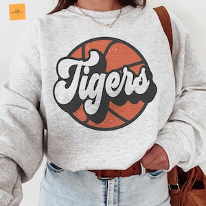 May include: A gray sweatshirt with a basketball graphic and the word "Tigers" in a retro font.